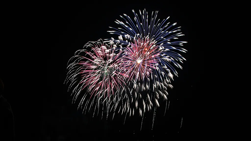 Buntes Feuerwerk in Blau, Rosa und Weiß am schwarzen Nachthimmel
