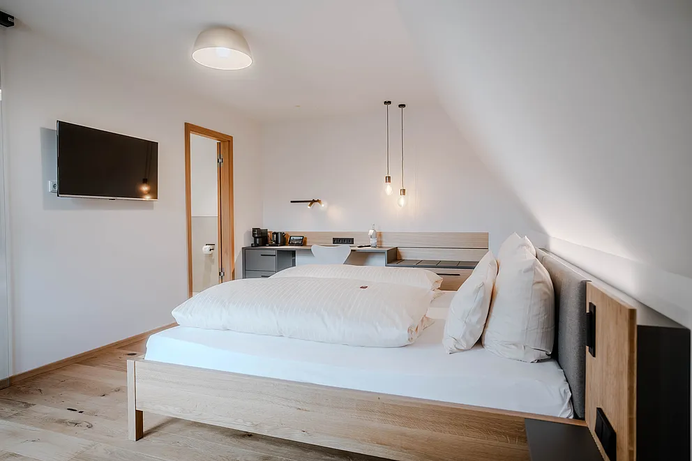 Superior-Plus-Zimmer im Haus Ehemalige Sparkasse mit Doppelbett unter der Dachschräge, Wand-TV und Schreibtisch