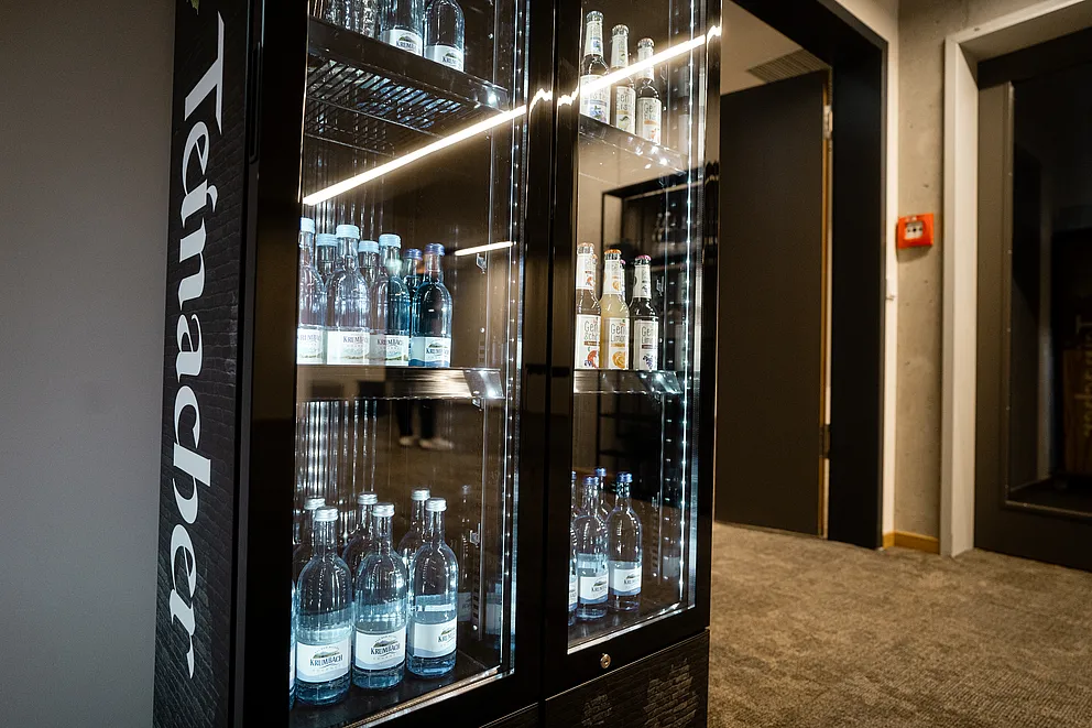 Beleuchteter Getränkekühlschrank mit Glastüren, gefüllt mit Mineralwasser und weiteren Getränken