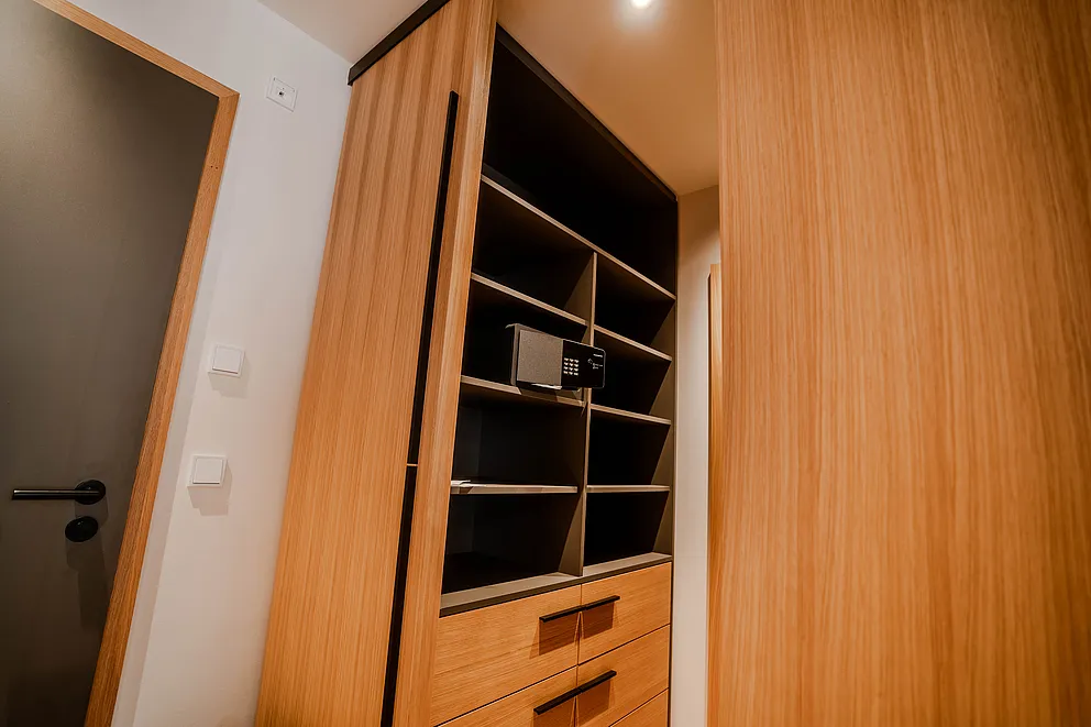 Offener Einbauschrank aus hellem Holz mit Regalfächern, Schubladen und einem Safe