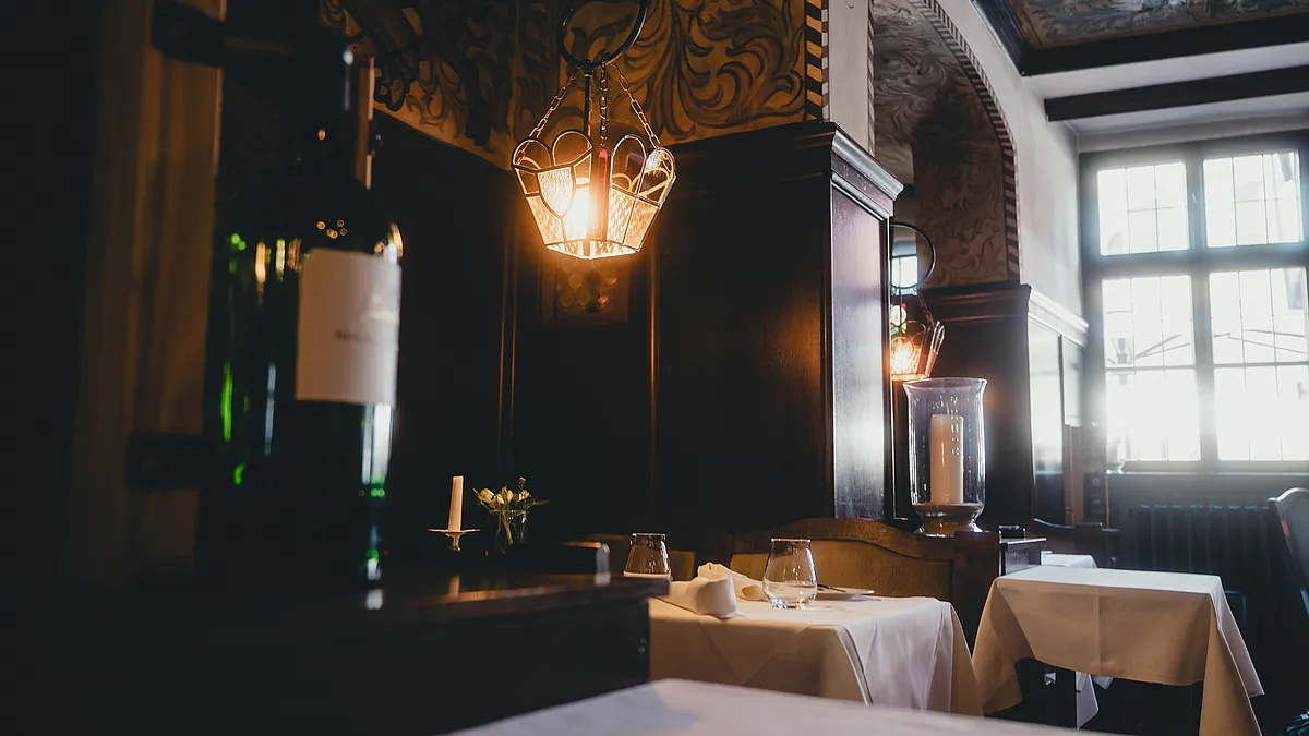 Restaurant im Hotel Deutsches Haus mit dunkler Holzvertäfelung, Laternenleuchte und weiß eingedeckten Tischen
