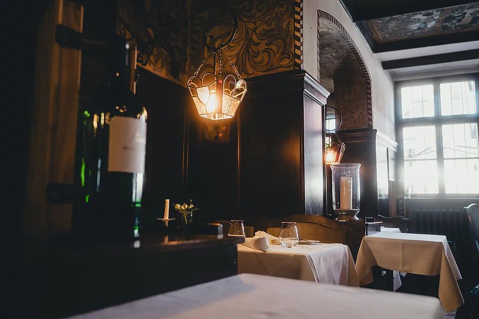 Restaurant im Hotel Deutsches Haus mit dunkler Holzvertäfelung, Laternenleuchte und weiß eingedeckten Tischen