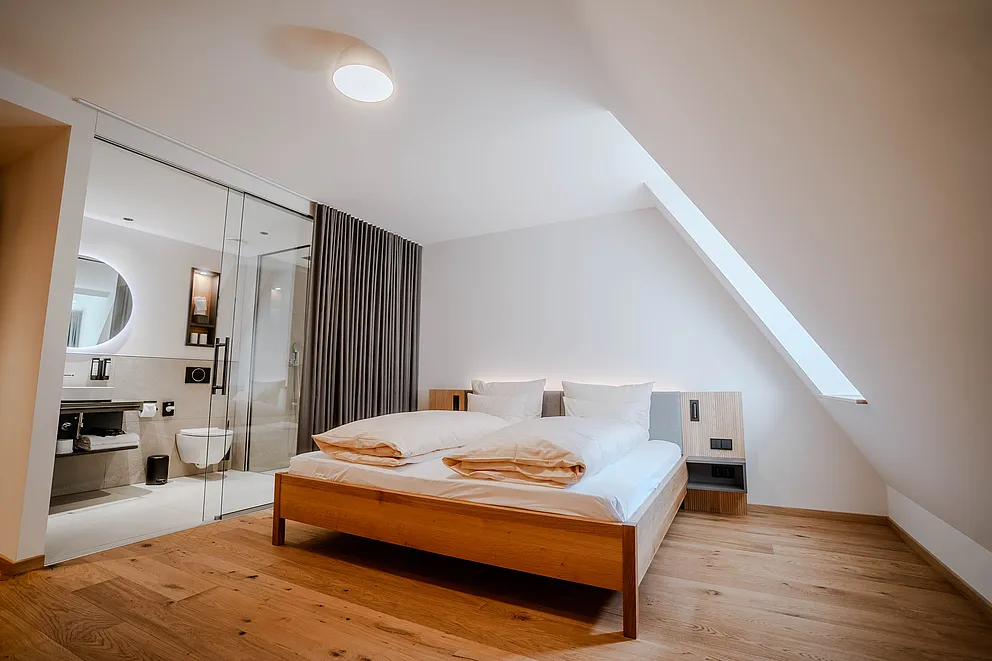 Komfortzimmer im Haus Ehemalige Sparkasse mit Doppelbett, Dachschräge und Bad hinter einer Glaswand