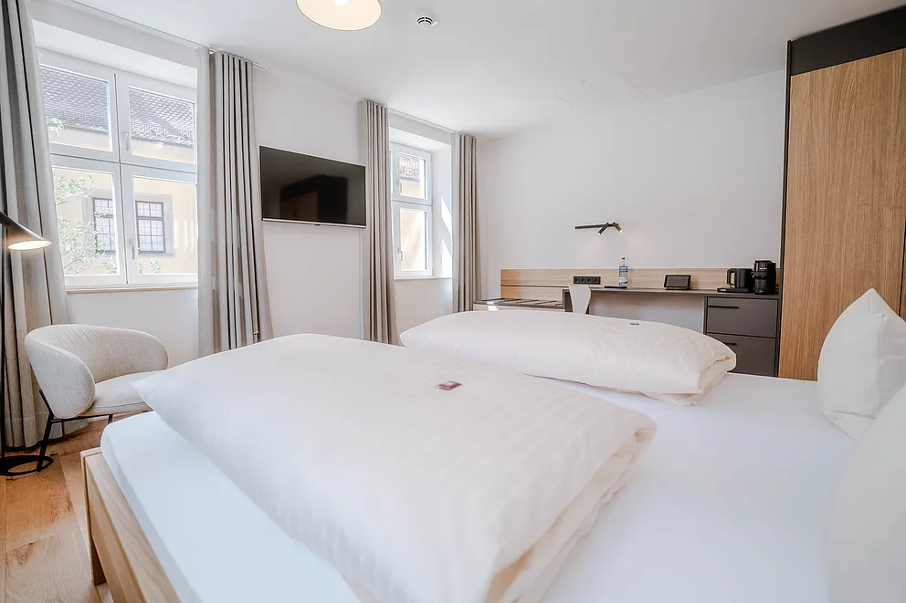 Superior-Zimmer im Haus Ehemalige Sparkasse mit Doppelbett, Sessel, Wand-TV, Schreibtisch und Holzschrank