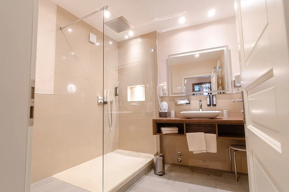 Bad der Hochzeitssuite im Stammhaus mit Glasdusche, Regenbrause und Wandnische, rechts Waschtisch mit beleuchtetem Spiegel