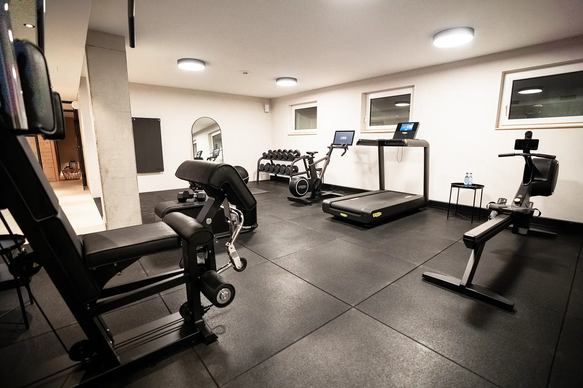 Fitnessraum im Haus Ehemalige Sparkasse mit Laufband, Ergometer, Rudergerät, Kraftgerät und Kurzhanteln auf Gummiboden